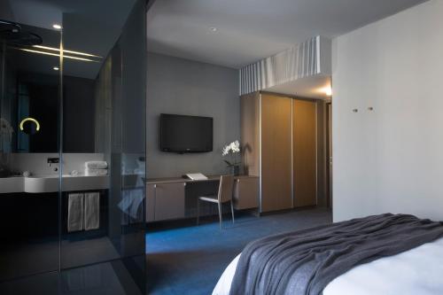 a bedroom with a bed and a bathroom with a sink at Hotel Cubo in Ljubljana