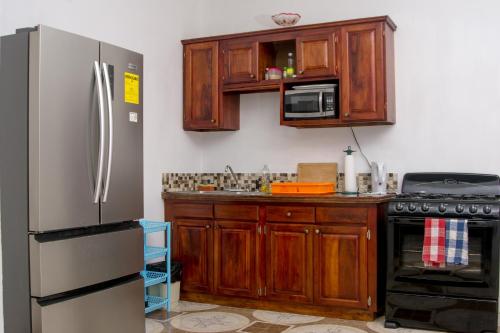 a kitchen with wooden cabinets and a stainless steel refrigerator at Veronica Homestay Lucea Jamaica in Lucea