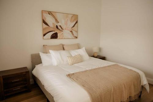 a bedroom with a large white bed with a picture on the wall at Vida Hamilton - 3 bed, 2 bath kids playground! in Hamilton