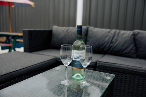 a bottle of wine and two wine glasses on a table at Vida Hamilton - 3 bed, 2 bath kids playground! in Hamilton