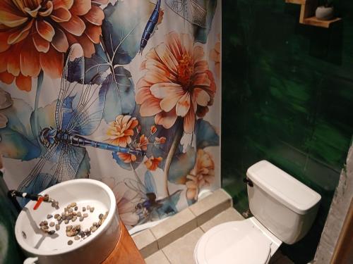 a bathroom with a toilet and a flower shower curtain at Hotel La Xinca in Antigua Guatemala