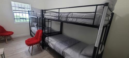 two bunk beds in a room with two red chairs at Large, Central, Lovely & Cozy 4bed/2bath - House by Everbank Stadium JACKSONVILLE in Jacksonville