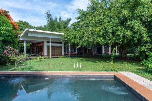 a house with a swimming pool in front of a yard at Mango Hill Pondicherry in Puducherry