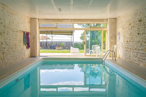 - une piscine dans une maison avec une grande fenêtre dans l'établissement Gite de Groupe piscine intérieure, à La-Gripperie-Saint-Symphorien