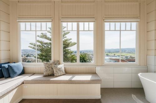 a bathroom with windows and a bench and a tub at Waratah On York in Launceston