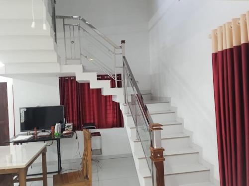 ChāliyārにあるGrifi Homestayの赤いカーテンと机のある部屋の階段
