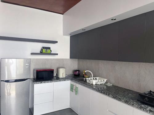 a kitchen with white cabinets and a stainless steel refrigerator at Eimas Hive in Kerobokan