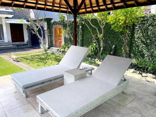 two white chairs sitting under an umbrella on a patio at Eimas Hive in Kerobokan
