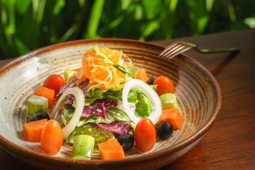 a bowl of salad with vegetables and a fork at Shintana Saya Residence in Siem Reap