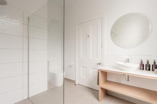 a white bathroom with a sink and a mirror at Waratah On York in Launceston