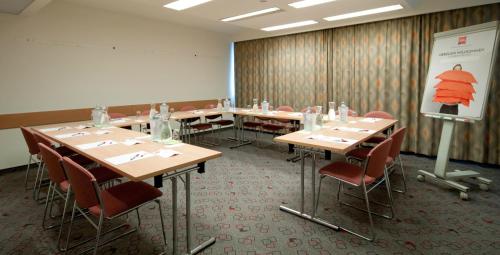 a conference room with tables and chairs and a screen at Ibis Wien Mariahilf in Vienna