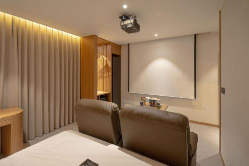 a waiting room with a chair and a projection screen at H Avenue Hotel Gwangju Cheomdan in Gwangju