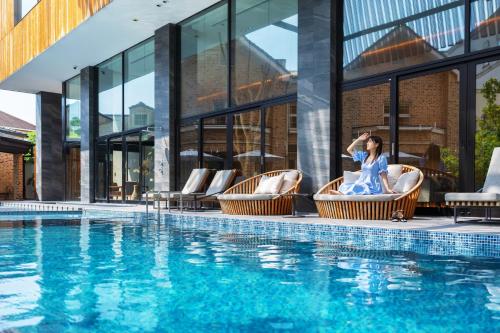 a woman sitting in chairs next to a swimming pool at Garden Terrace Fukuoka in Fukuoka