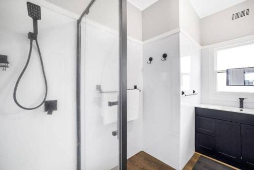 a white bathroom with a shower and a sink at Seaspray home in Tarraville