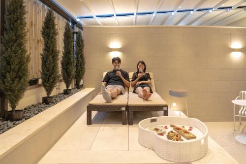 a man and woman sitting on a bench in a lobby at H Avenue Hotel Gwangju Cheomdan in Gwangju
