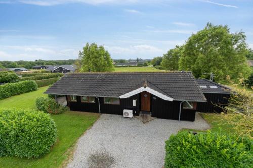 a house with a black roof on a gravel driveway at Well-Equipped Summer House Near Skovmose in Neder Lysabild