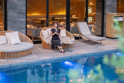 a woman sitting in chairs next to a swimming pool at Garden Terrace Fukuoka in Fukuoka