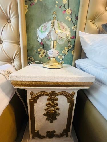 a table with a lamp on it next to two beds at Victorian Suites at Brenthill Baguio City Center in Tuding