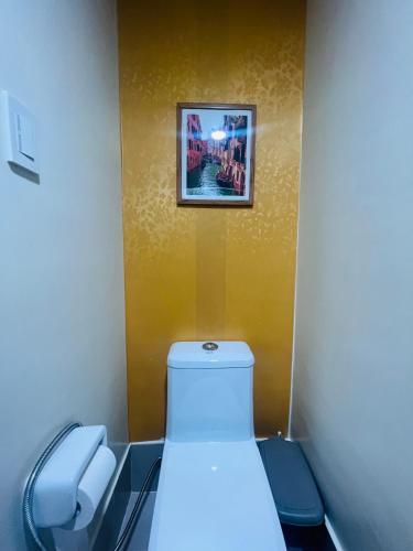 a bathroom with a toilet and a picture on the wall at Victorian Suites at Brenthill Baguio City Center in Tuding