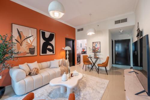 a living room with a white couch and an orange wall at Stylish 1BR Apartment! Near Metro & Stroll to Dubai Marina in Dubai