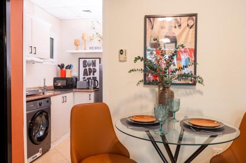a kitchen with a glass table and orange chairs at Stylish 1BR Apartment! Near Metro & Stroll to Dubai Marina in Dubai