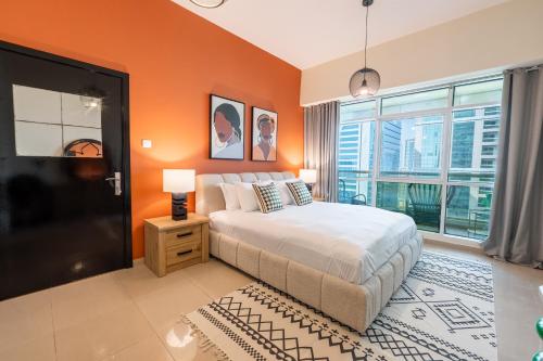 a bedroom with orange walls and a bed with a window at Stylish 1BR Apartment! Near Metro & Stroll to Dubai Marina in Dubai