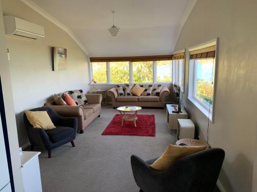 a living room with couches and chairs and a table at Beach Home with 3 double bedrooms and amazing sea views in Point Howard