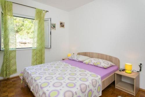 ein Schlafzimmer mit einem Bett mit violetter Bettwäsche und einem Fenster in der Unterkunft Apartments Stipo - Two Bedroom Apartment with Balcony and Sea View A3 in Drače