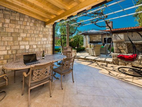 a patio with a table and chairs with a laptop on it at Villa Mia -Three-Bedroom Villa with Swimming Pool in Trsteno
