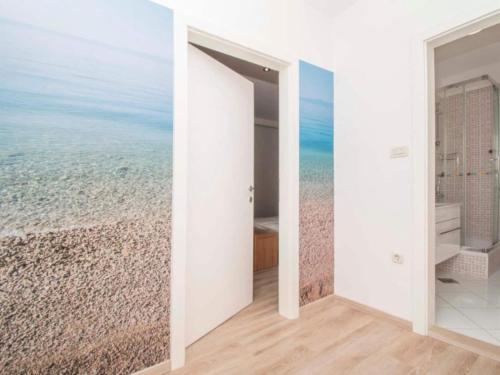 an open door to a bathroom with a beach mural at Apartments Antonio - Comfort One-Bedroom Apartment with Balcony and Sea View - 4 in Tučepi