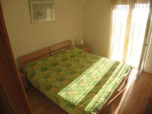 a bedroom with a bed with a green quilt on it at Apartments Paloc - Standard One-bedroom Apartment with Balcony uti in Bol