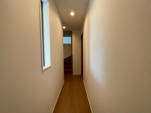 a hallway with a white wall and a window at Starry Ocean in Tokyo