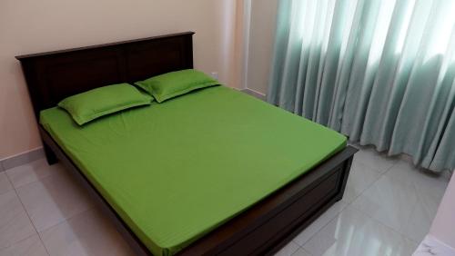 una cama con sábanas verdes y una manta verde en SK Luxury Apartments, en Wattala