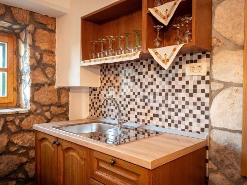 eine Küche mit einem Waschbecken und einer gefliesten Wand in der Unterkunft Villa Lazini Dvori - Two Bedroom Stone House Villa with Private Pool in Staševica