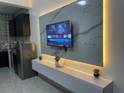 a kitchen with a counter with a tv on a wall at Lavender Cozy apartment in Namugongo
