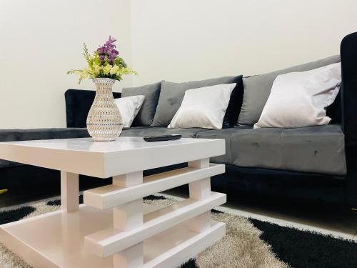 a living room with a couch and a vase on a coffee table at Lavender Cozy apartment in Namugongo