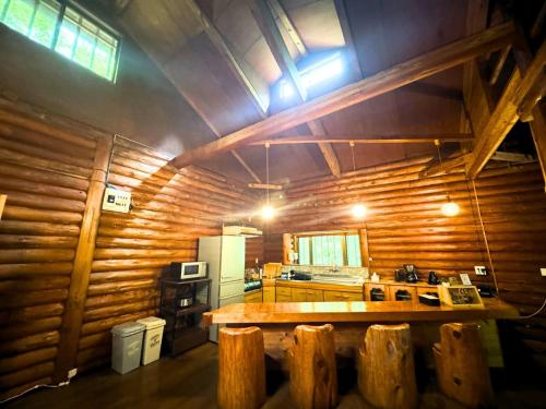 a kitchen with wooden walls and a wooden table at 貸別荘モザンピーク 完全貸切ログハウス in Kirishima