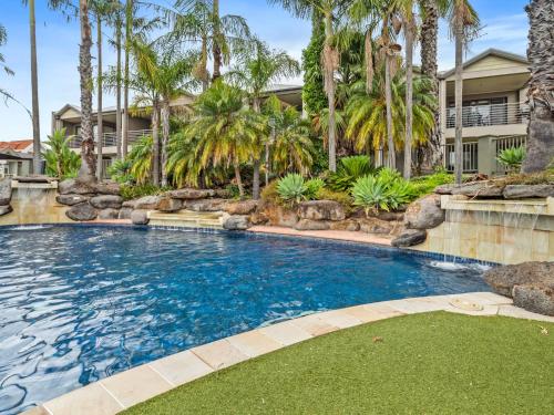 a swimming pool with palm trees in front of a house at Yarrawonga Lakeside Apartment 27 in Mulwala