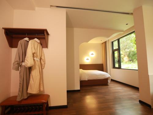 a room with a bed and a robe hanging on a wall at 张家界喜屋民宿 in Zhangjiajie