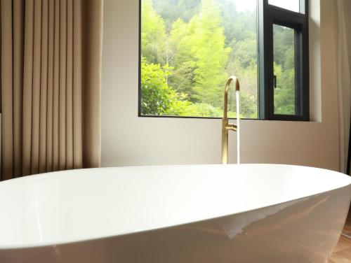 a white bath tub in a bathroom with a window at 张家界喜屋民宿 in Zhangjiajie