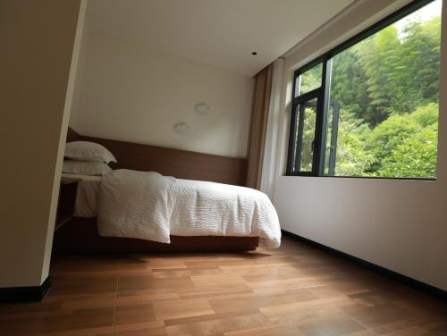 a bedroom with a bed and a large window at 张家界喜屋民宿 in Zhangjiajie