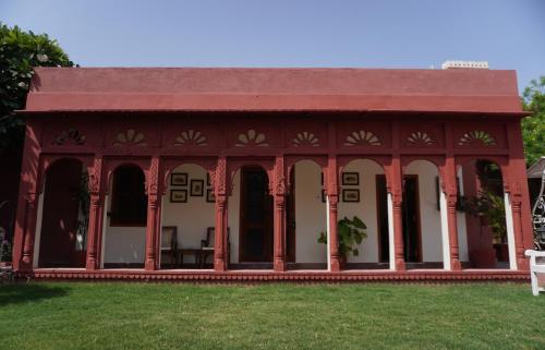 a building with a red roof on a grass field at Cavalry Villa bikaner in Bikaner