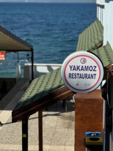 a sign for a restaurant on a bench next to the water at Dardanos Yerleşkesi in Hamidiye