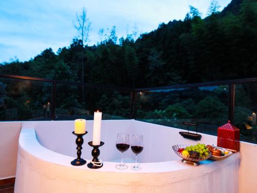 a table with two candles and wine glasses on a balcony at 张家界喜屋民宿 in Zhangjiajie