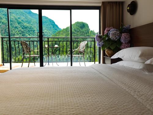 a bedroom with a bed and a balcony with chairs at 张家界喜屋民宿 in Zhangjiajie