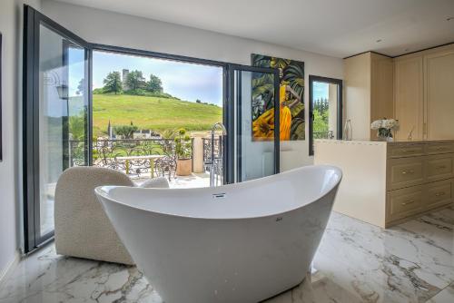 une baignoire dans une salle de bain avec une grande fenêtre dans l'établissement Maison de vacances Carsac-de-Gurson, à Carsac-de-Gurson