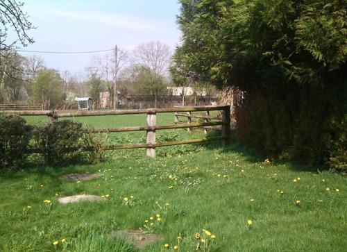 a wooden fence in a field with green grass at Petit Chalet romantique en normandie in Le Pin-au-Haras