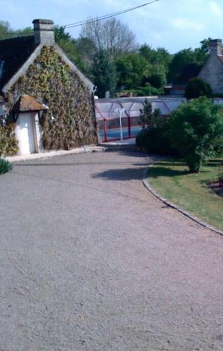 a stone house with a fence and a driveway at Petit Chalet romantique en normandie in Le Pin-au-Haras