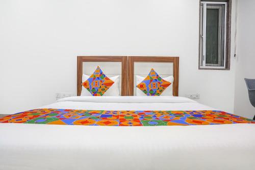 a white bed with a colorful comforter on it at FabHotel Aerosky - Nr Yashobhoomi Convention Centre in New Delhi