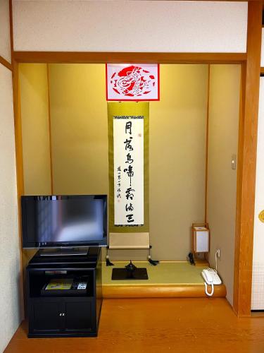 a room with a television and a sign on the wall at 高野山 宿坊 総持院 -Koyasan Shukubo Sojiin- in Koyasan